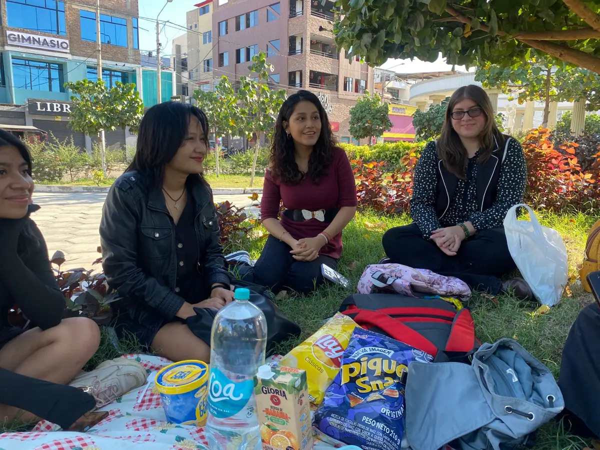 Participantes conversando en una manta de picnic en un parque